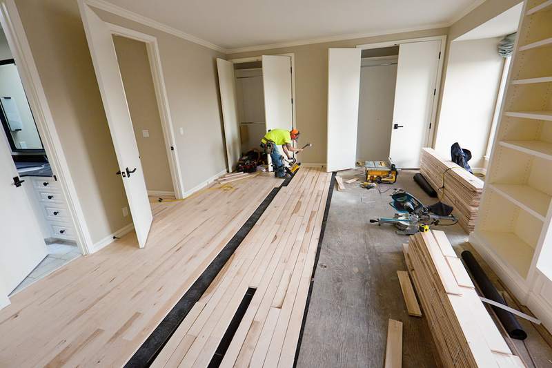 Contractor installs hardwood floors in a fixer-upper home.