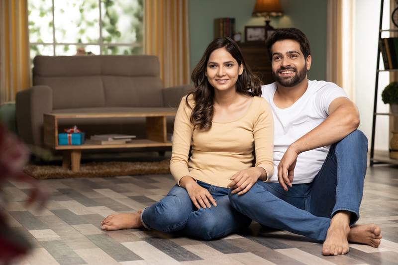 Smiling couple sits together on the floor of their new home.