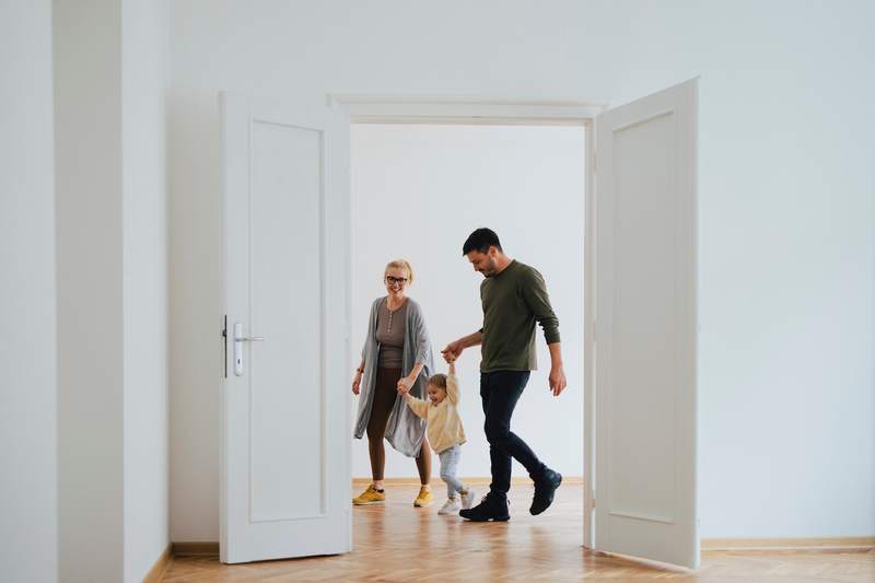 parents with their young daughter walking through an empty house