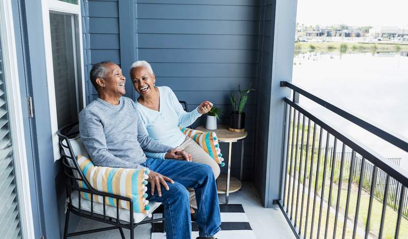 Older couple sitting on the balcony of their home.