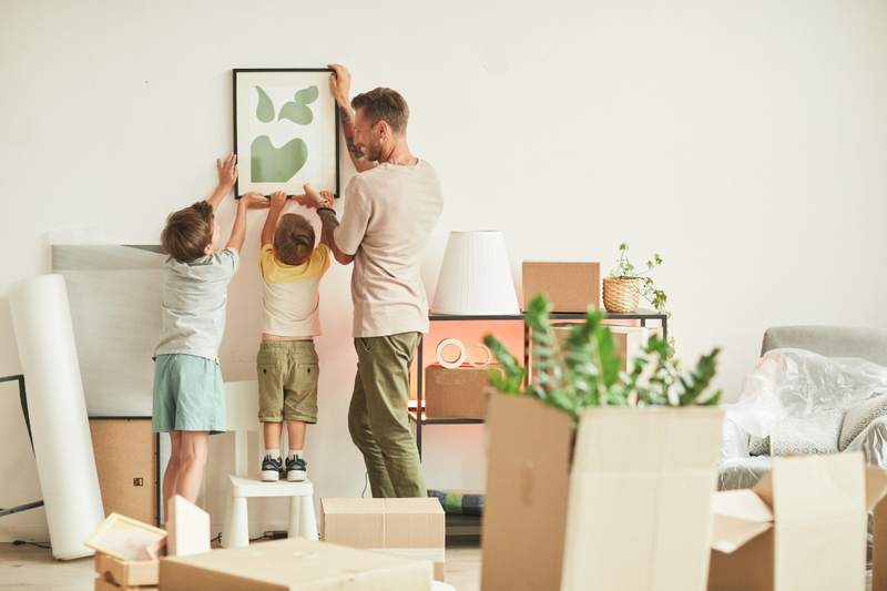 Young family putting up a picture in their new home after moving in.