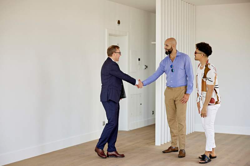 Agent shakes hands with diverse couple in an empty home.
