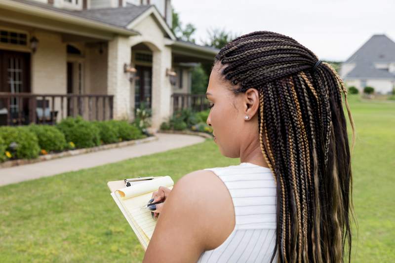 Appraiser takes notes outside home for sale.