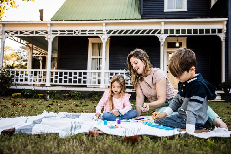Family paints pictures outside rural home.