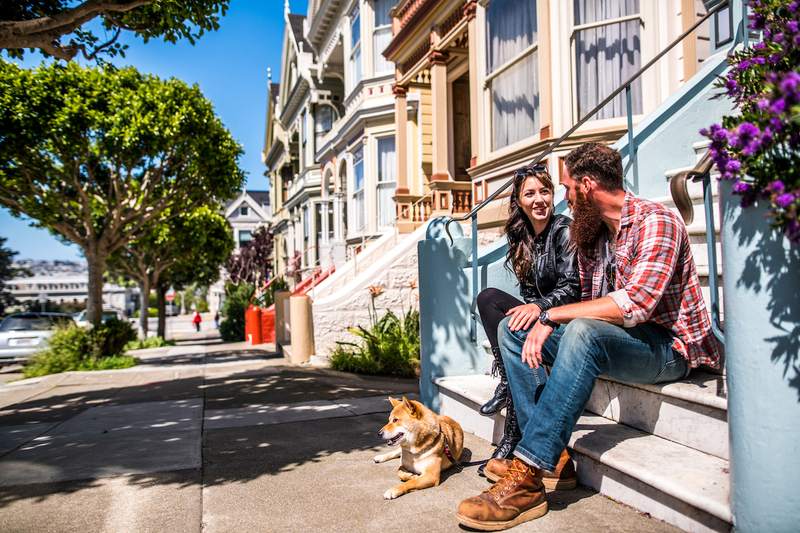 A couple and their dog sit outside their new townhouse.