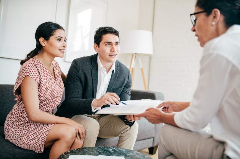 A couple asks questions during an interview with a real estate agent candidate.
