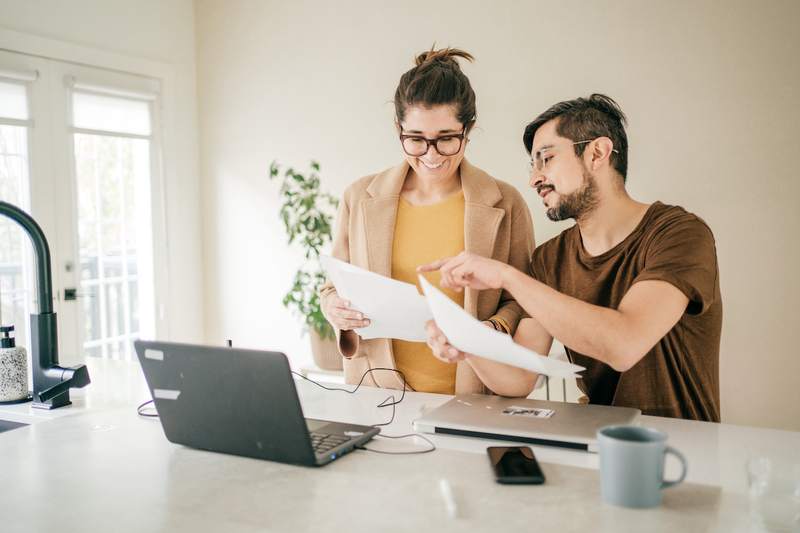Couple compares mortgages with laptop on counter.